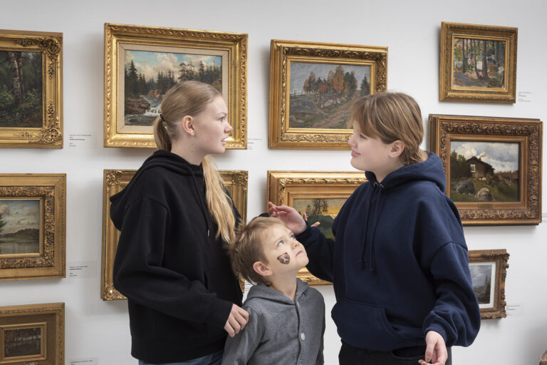 Kolme lasta keskustelevat museossa.