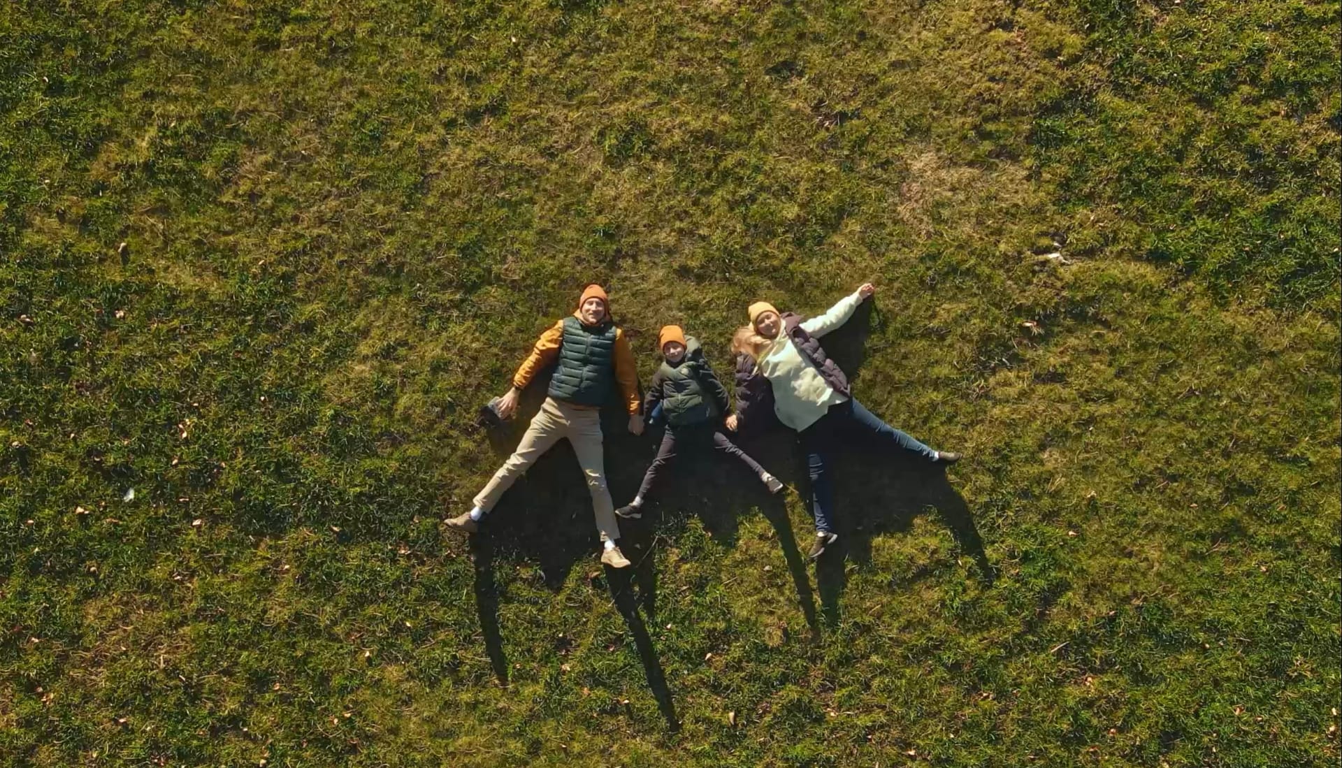 Perhe makaa nurmikollakäsi kädessä ylhäältä kuvattuina